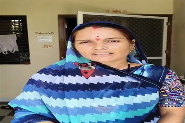 नीले रंग की साड़ी में घर के सामने खड़ी एक महिला